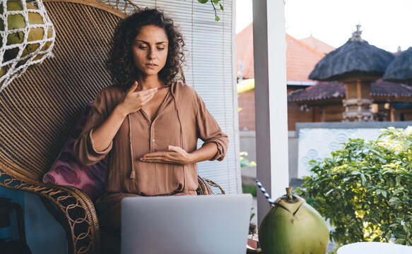 Skilled female explaining theta holistic healing during online meditation on courses with web followers using laptop computer outdoors, Caucaisan coacher have web seminar on modern netbook device