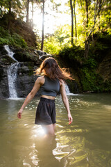 a young woman stands near a waterfall