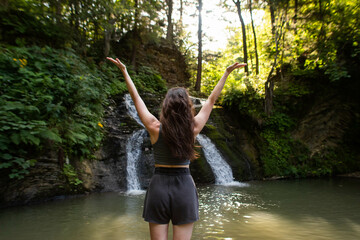 a young woman stands near a waterfall