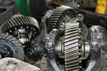 Large gears of a truck. The engine and shaft with gears are disassembled. Black, metal engine parts.