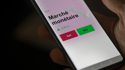 Un investisseur analyse un fonds etf marché monétaire sur un graphique. Un téléphone affiche le cours de l'ETF Marché monétaire