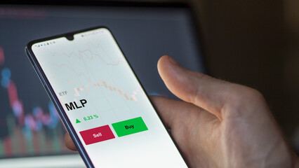 Un investisseur analyse un fonds etf mlp sur un graphique. Un téléphone affiche le cours de l'ETF MLP