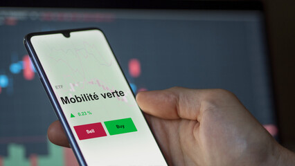 Un investisseur analyse un fonds etf mobilité verte sur un graphique. Un téléphone affiche le cours de l'ETF Mobilité verte