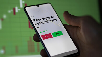 Un investisseur analyse un fonds etf robotique et automatisation sur un graphique. Un téléphone affiche le cours de l'ETF Robotique et automatisation
