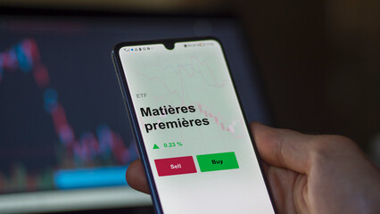 Un investisseur analyse un fonds etf matières premières sur un graphique. Un téléphone affiche le cours de l'ETF Matières premières