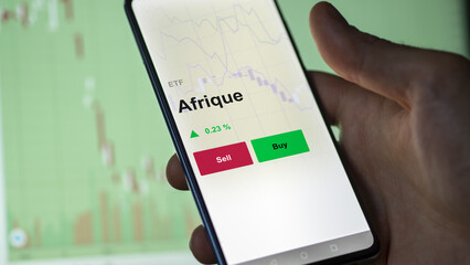 Un investisseur analyse un fonds etf afrique sur un graphique. Un téléphone affiche le cours de l'ETF. Texte en français francais Afrique