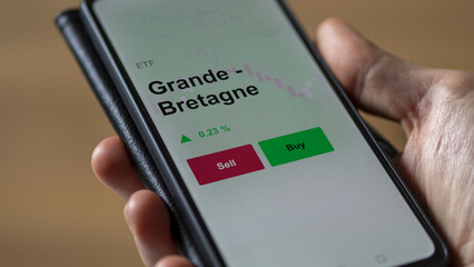 Un investisseur analyse un fonds etf grande - bretagne sur un graphique. Un téléphone affiche le cours de l'ETF. Texte en français francais Grande - Bretagne