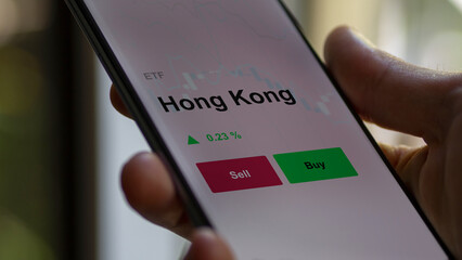 Un investisseur analyse un fonds etf hong kong sur un graphique. Un téléphone affiche le cours de l'ETF. Texte en français francais Hong Kong