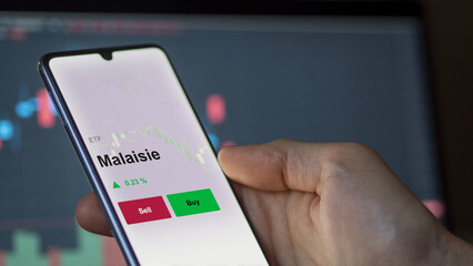 Un investisseur analyse un fonds etf malaisie sur un graphique. Un téléphone affiche le cours de l'ETF. Texte en français francais Malaisie