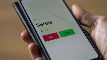 Un investisseur analyse un fonds etf serbie sur un graphique. Un téléphone affiche le cours de l'ETF. Texte en français francais Serbie