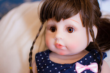 Little girl doll with brown hair and pink cheeks, she looks at you with big brown eyes.