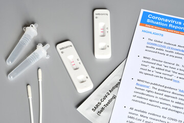 two SARS‑CoV‑2 antigen test kit for self testing with positive results with paper documents. One step coronavirus antigen rapid test, saliva swab on grey background. close-up