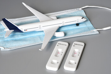 Covid travel concept. Airplane on protection mask with two covid 19 antigen test kits and negative results.