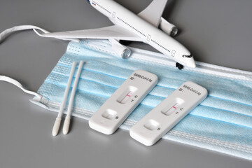 Covid travel concept. Airplane on protection mask with two covid 19 antigen test kits and negative results.