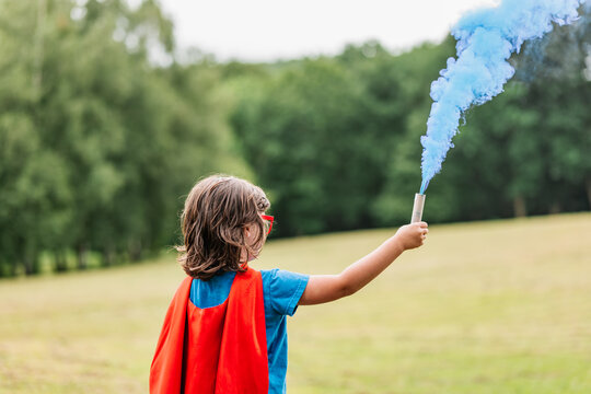Little superhero waving blue smoke bomb