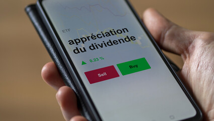 Un investisseur analyse un fonds etf appréciation du dividende sur un graphique. Un téléphone affiche le cours de l'ETF. Texte en français francais appréciation du dividende