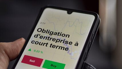 Naklejka premium Un investisseur analyse un fonds etf obligation d'entreprise à court terme sur un graphique. Un téléphone affiche le cours de l'ETF. Texte en français francais Obligation d'entreprise à court terme
