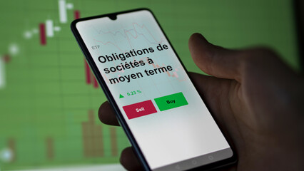 Un investisseur analyse un fonds etf obligations de sociétés à moyen terme sur un graphique. Un téléphone affiche le cours de l'ETF. Texte en français francais Obligations de sociétés à moyen terme