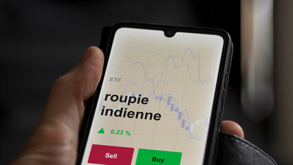 Un investisseur analyse un fonds etf roupie indienne sur un graphique. Un téléphone affiche le cours de l'ETF. Texte en français francais roupie indienne