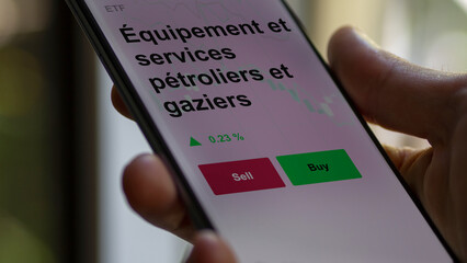 Un investisseur analyse un fonds etf équipement et services pétroliers et gaziers sur un graphique. Un téléphone affiche le cours de l'ETF. Texte en français francais.