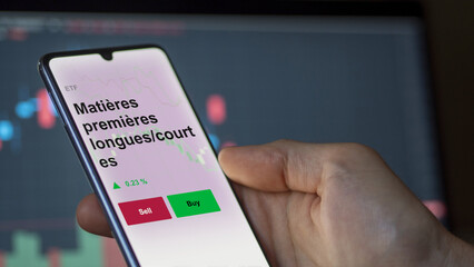 Un investisseur analyse un fonds etf matières premières longues/courtes sur un graphique. Un téléphone affiche le cours de l'ETF. Texte en français francais Matières premières longues/courtes