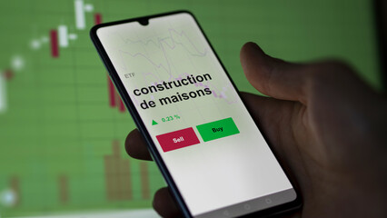 Un investisseur analyse un fonds etf construction de maisons sur un graphique. Un t&eacute;l&eacute;phone affiche le cours de l'ETF. Texte en fran&ccedil;ais francais construction de maisons