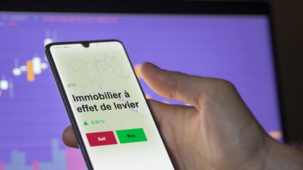 Un investisseur analyse un fonds etf immobilier à effet de levier sur un graphique. Un téléphone affiche le cours de l'ETF. Texte en français francais Immobilier à effet de levier