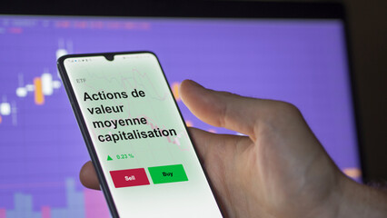 Un investisseur analyse un fonds etf actions de valeur moyenne capitalisation sur un graphique. Un téléphone affiche le cours de l'ETF. Texte en français francais