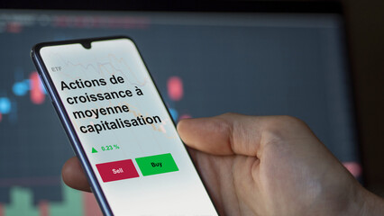 Un investisseur analyse un fonds etf actions de croissance à moyenne capitalisation sur un graphique. Un téléphone affiche le cours de l'ETF. Texte en français francais 