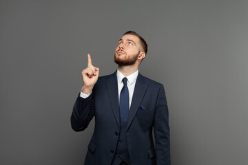 Young business man pointing up against gray wall banner background