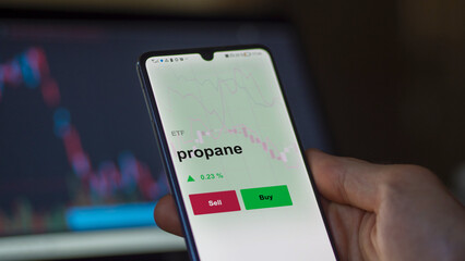 Un investisseur analyse un fonds etf propane sur un graphique. Un téléphone affiche le cours de...