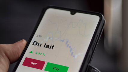 Un investisseur analyse un fonds etf du lait sur un graphique. Un t&eacute;l&eacute;phone affiche le cours de l'ETF laitier. Texte en fran&ccedil;ais, francais. 