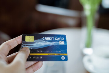 Woman holding credit card in coffee shop.