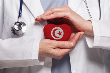 Tunisian doctor holding heart with flag of Tunisia background. Healthcare, charity, insurance and medicine concept