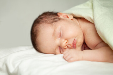 Newborn baby lying on bed on white background