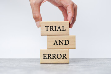 Businessman hand picked wooden blocks with words 'trial and error'. Business concept.  