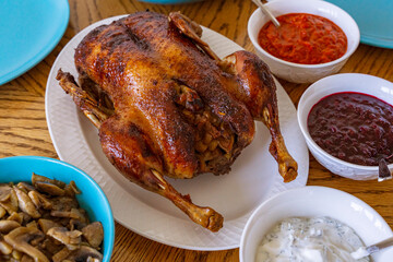Roasted whole Peking duck with apples and sauces in gravy boats. Traditional holiday dish. Fried crust with honey. High quality. Homemade holiday dinner.