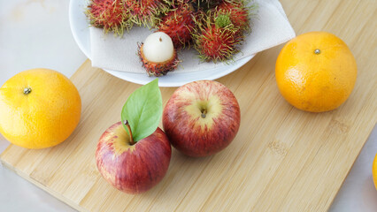 Two apple on center of picture. Orange on wood plate. Mix fruit for healthy. Get vitamin from nature.  Concept photo from kitchen.