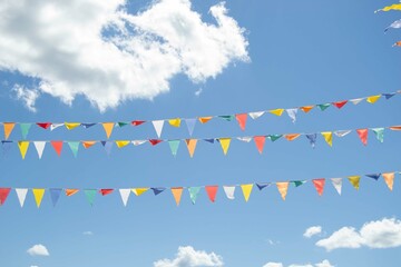 Multicolored festival flags on a blue sky background on a sunny summer day. 