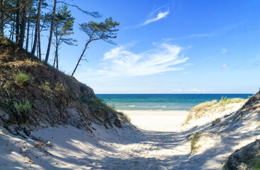 Entrance to a sandy beach through dunes, Baltic Sea near Łeba, Poland, Europe. Summer, little waves on the water, blue sky with white clouds. - obrazy, fototapety, plakaty