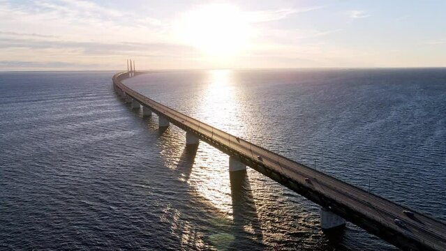 Aerial view of Oresund bridge at the sunset in summer. Cinematic shot of long bridge between Sweden and Denmark. Sunset over the sea and huge bridge. High quality 4k footage