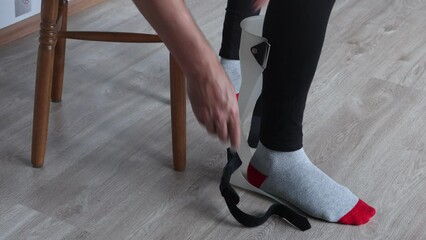 Foot drop splint for support and stabilizer ankle, someone fixes orthosis on leg.