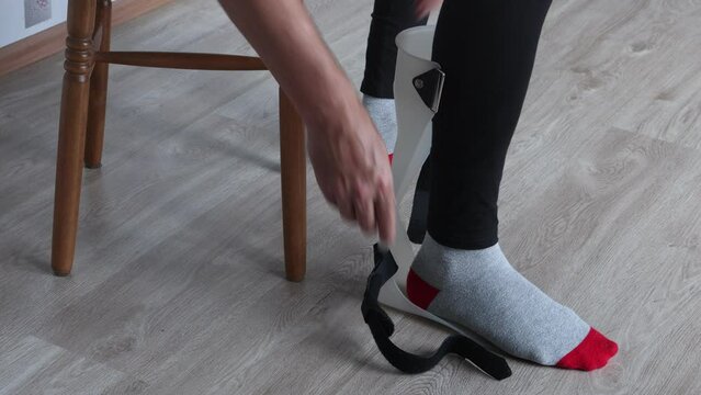 Foot drop splint for support and stabilizer ankle, someone fixes orthosis on leg.