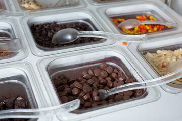A view of several containers full of toppings in a frozen yogurt or ice cream shop setting.