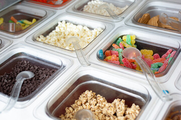 A view of several containers full of toppings in a frozen yogurt or ice cream shop setting.