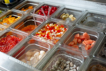 A view of several containers full of toppings in a frozen yogurt or ice cream shop setting.