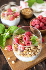 Healthy breakfast menu concept. Home made granola breakfast. Glass of parfait made of granola, berries raspberry, yogurt with chia seeds on rustic table.