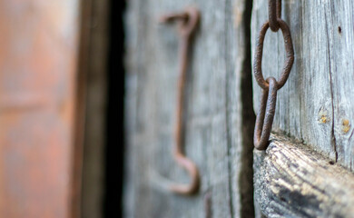 Isolated old rusty door latch on a wooden door. Close-up. Problematic weathered panels. Old wall texture background. Detail of an old wooden door with a rusty door latch.