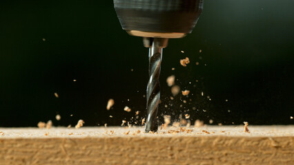 Freeze motion of a drill bit drilling into wood, macro shot - obrazy, fototapety, plakaty