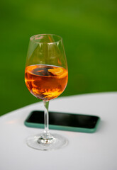 Glass of prosecco with mobile phone on table outdoor